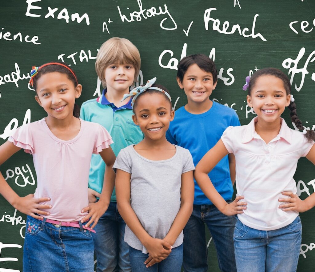 Composite Image Of Cute Pupils Smiling At Camera In Classroom