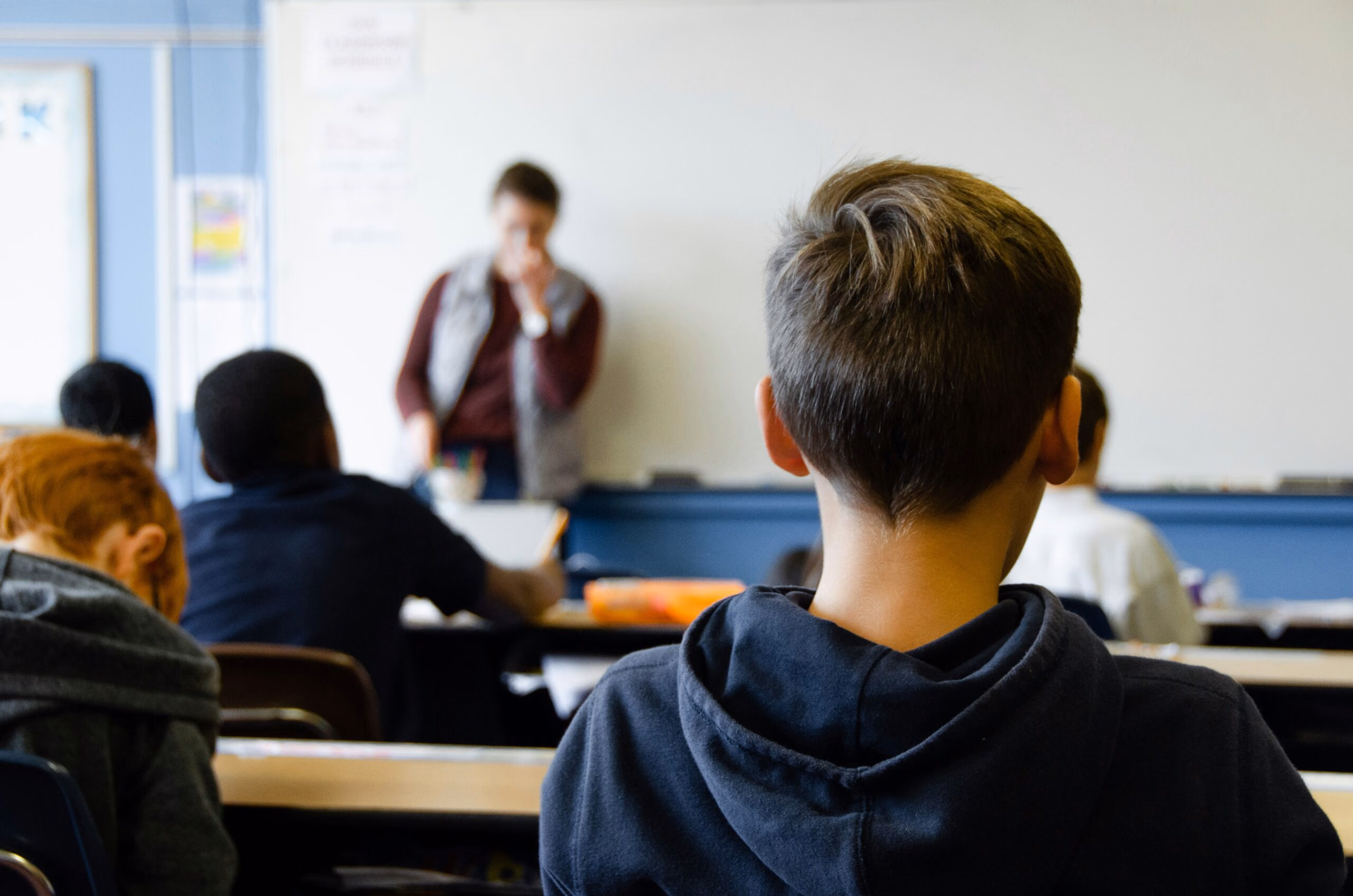 A classroom full of students with a teacher in front of a whiteboard